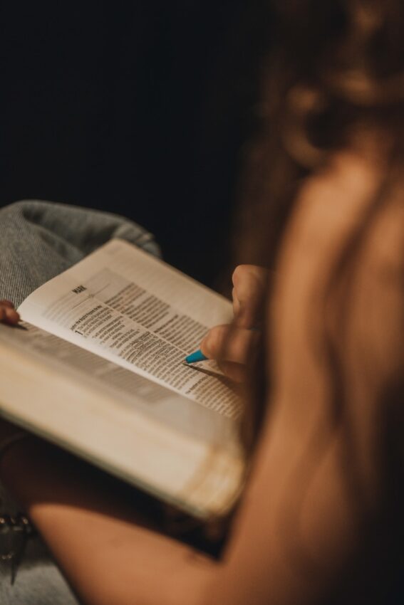 A person reading a book with a blue fingernail.