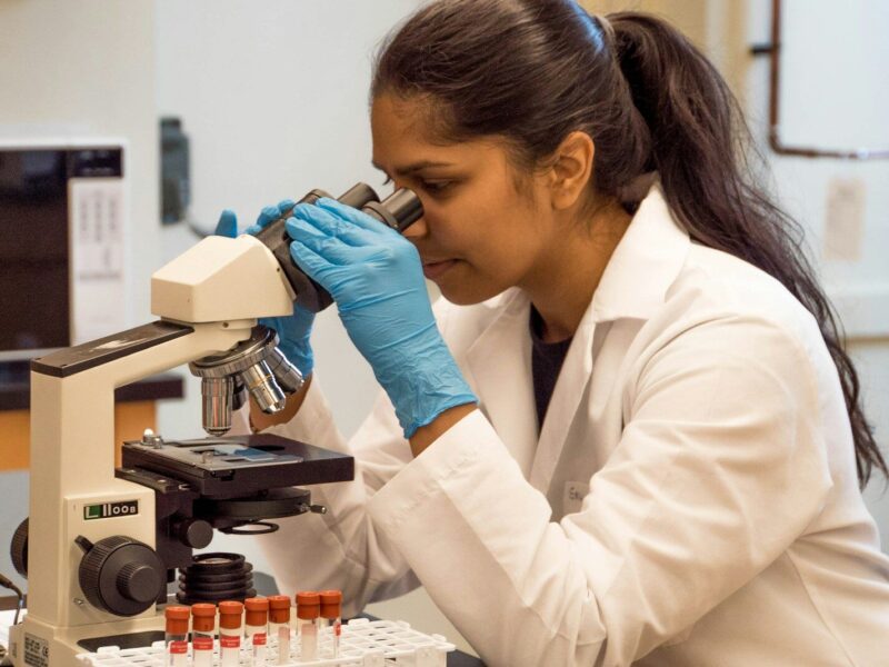 woman looking on microscope inside room