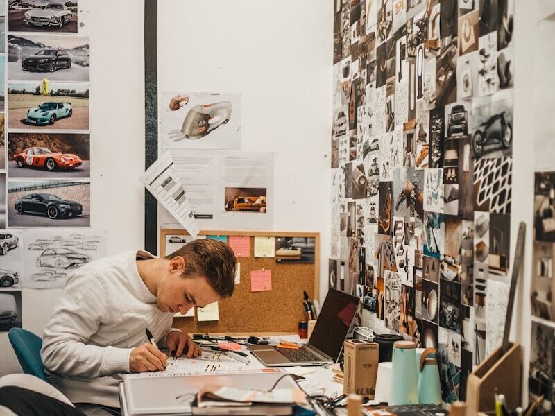man writing beside wall with car photos