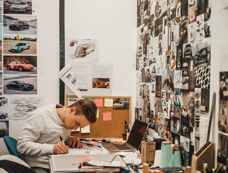 man writing beside wall with car photos