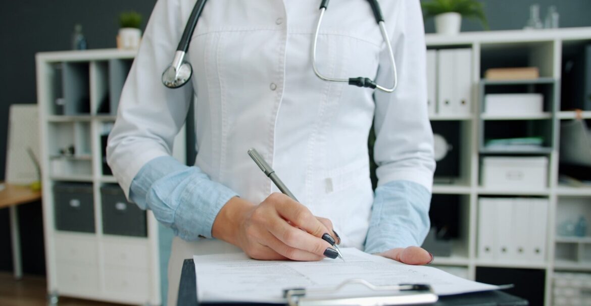Doctor writing on clipboard in office