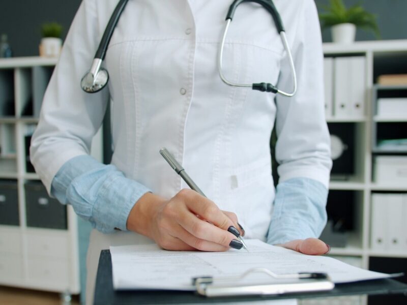 Doctor writing on clipboard in office