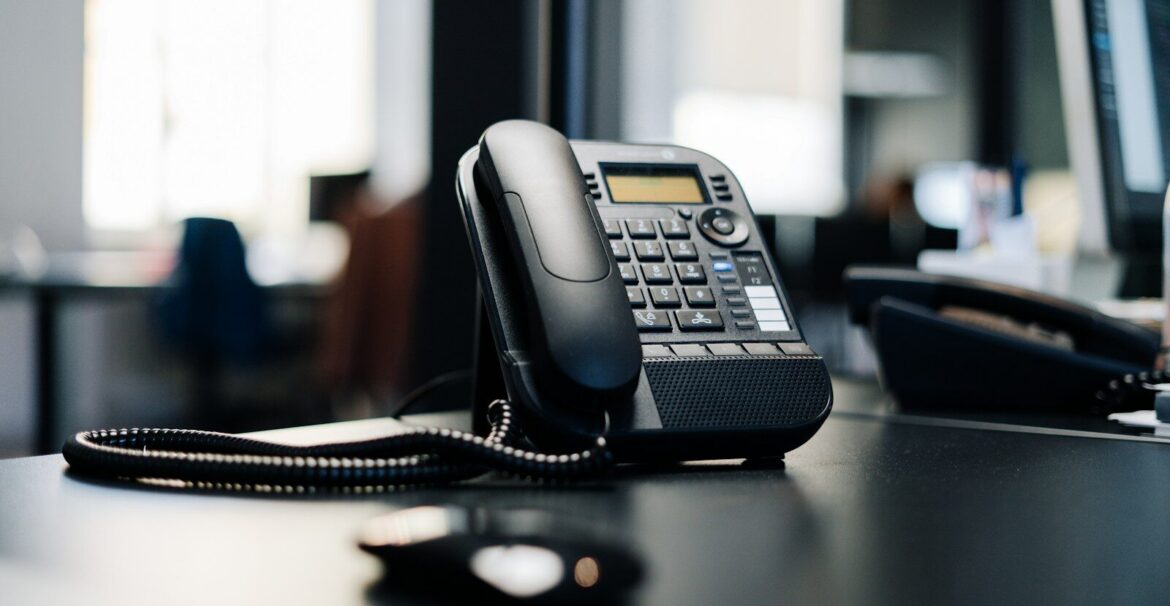 black ip desk phone on black wooden table