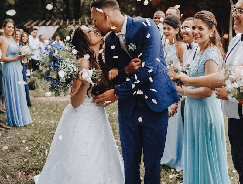 man in blue suit kissing woman in white wedding dress
