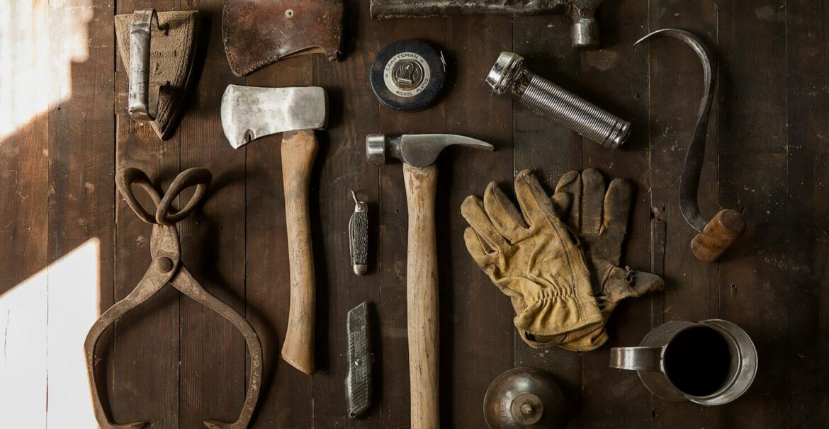 clothes iron, hammer, axe, flashlight and pitcher on brown wooden table