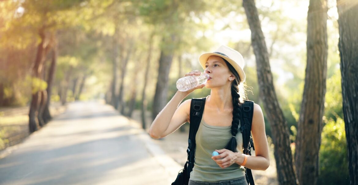 a woman in a hat drinking water from a bottle