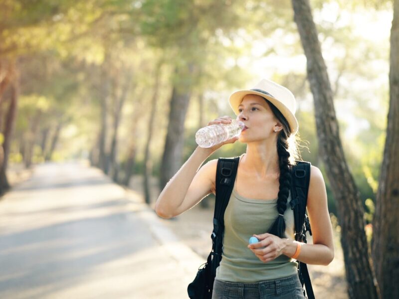 a woman in a hat drinking water from a bottle